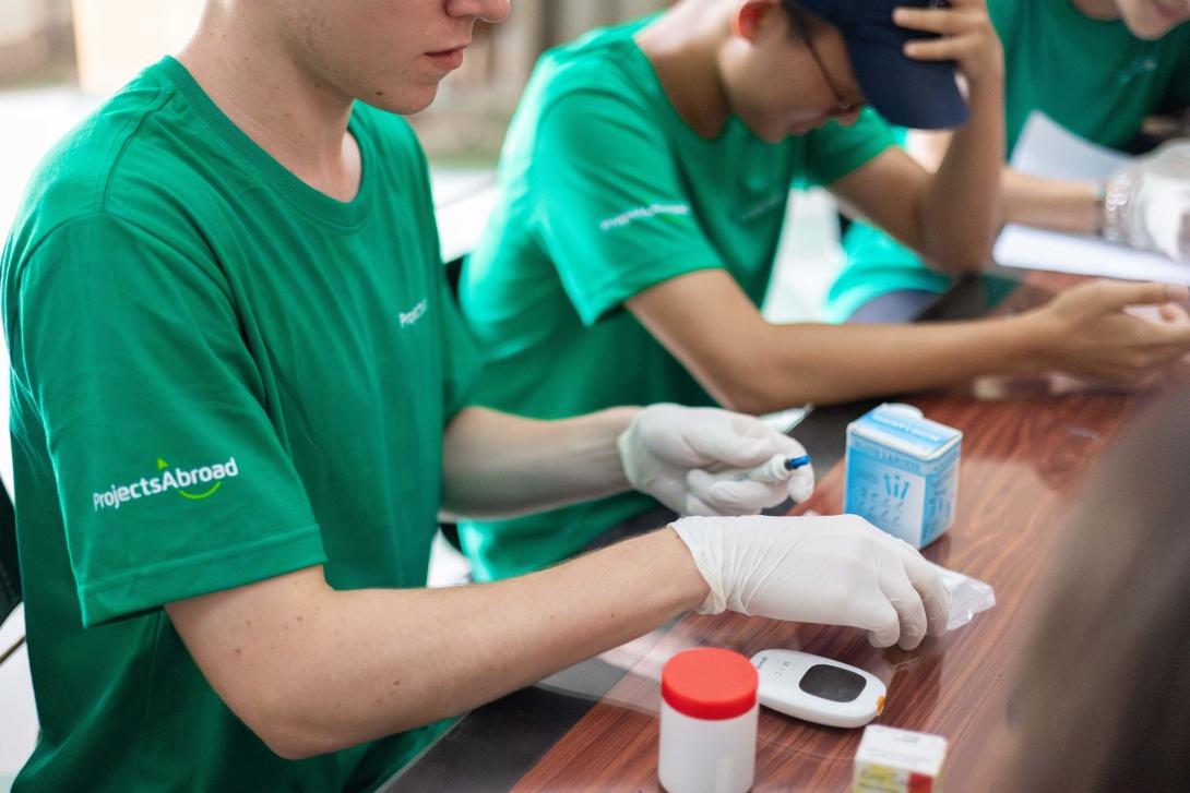 Volunteer using glucose monitor in Cambodia